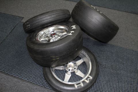 2003 Ford Crown Victoria - group of drag slick tires mounted on polished five-spoke wheels rests on a checkered floor mat.