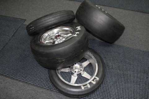 2003 Ford Crown Victoria - Drag slick tires on polished wheels with white MH sidewall lettering sit grouped on a checkered mat.