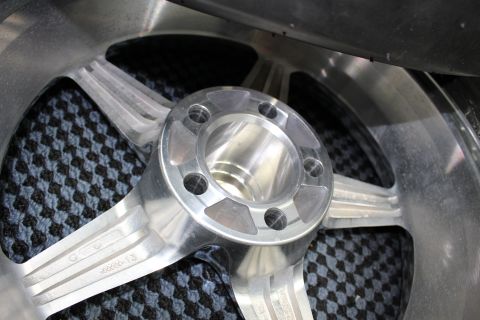 2003 Ford Crown Victoria - close-up of a polished aluminum wheel center shows the machined hub and five lug holes over a carbon-pattern mat.