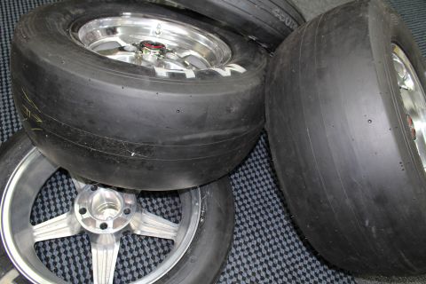 2003 Ford Crown Victoria - Several drag slick tires mounted on polished aluminum wheels rest together on a checkered floor mat.