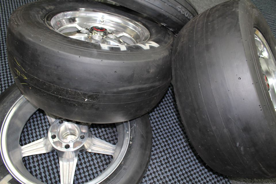 Drag slick tires on polished wheels resting on a checkered mat