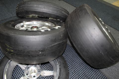2003 Ford Crown Victoria - group of drag slick tires on polished wheels, one with yellow paint marks, rests on a checkered mat.