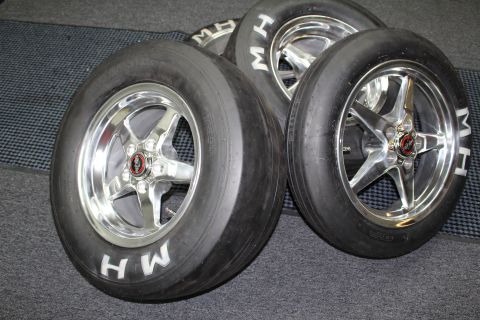 2003 Ford Crown Victoria - Two polished five-spoke drag wheels on slicks with white MH lettering rest side by side on a mat.