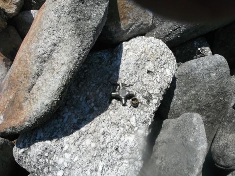 1988 Ford Bronco - A universal joint part is visible on a rock surface, surrounded by other large stones.