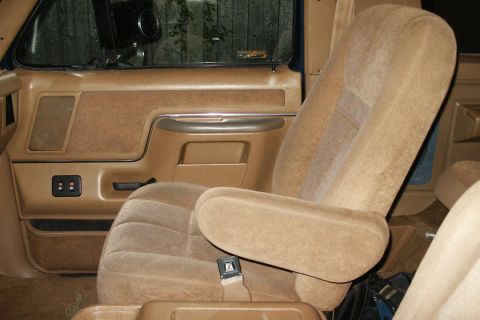 1991 Ford Bronco - The interior features tan cloth seats and door panels, with a visible armrest and seatbelt.