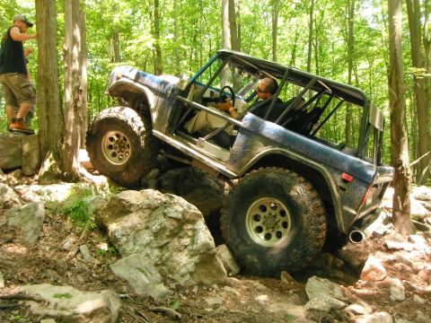 1988 Ford Bronco - This modified SUV navigates a challenging rocky trail, demonstrating its off-road capabilities.