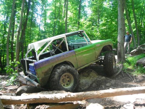 1988 Ford Bronco - Modified Ford Bronco navigates a rocky trail in a wooded area.