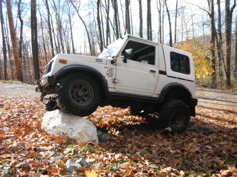 1991 Suzuki Samurai - This 1991 Suzuki Samurai is navigating a rocky obstacle on a dirt path surrounded by autumn trees.