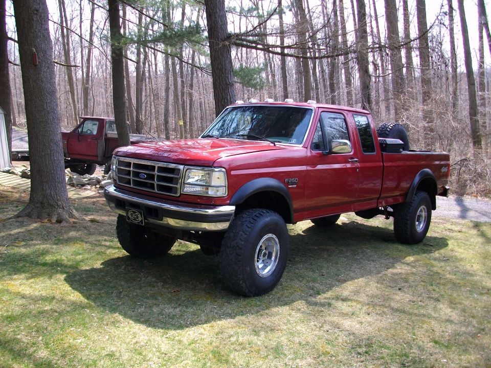 Red 1996 Ford F-250 crew cab pickup truck with large tires parked outdoors