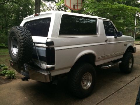 1994 Ford Bronco - This white Ford Bronco is shown from the rear quarter angle, a spare tire mounted externally.