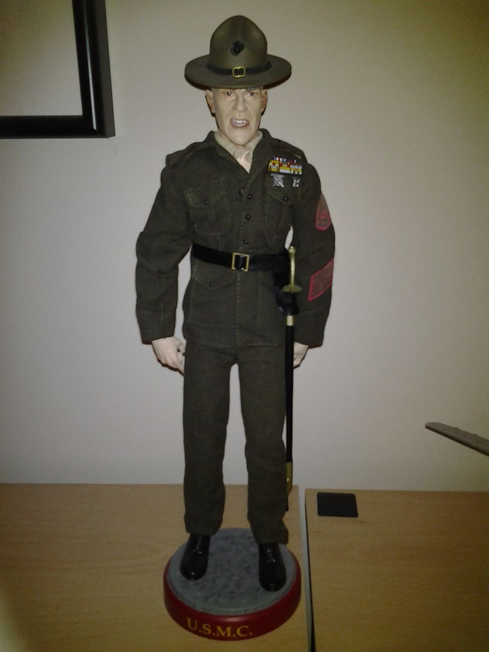 USMC drill instructor mannequin in uniform with sword and hat, standing on a display base