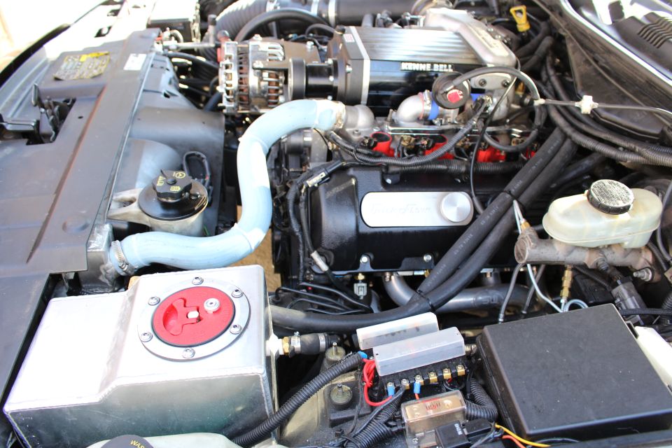 Supercharged engine with blue hose, red battery switch and reservoir