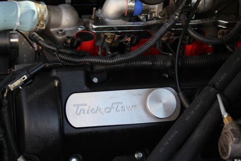 2003 Ford Crown Victoria - Close-up of a black engine valve cover bearing a polished 'Trick Flow' nameplate, with a light-blue intake hose and red engine block visibl…