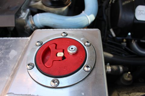 2003 Ford Crown Victoria - Close-up of an aluminum fuel cell topped by a red flip-style locking filler cap, mounted in a vehicle engine compartment.