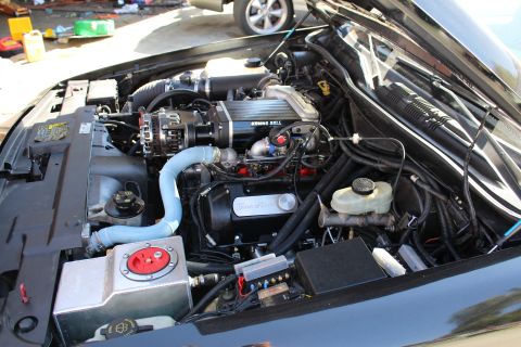 2003 Ford Crown Victoria - Wide shot of an open engine compartment featuring a Kenne Bell supercharger, light-blue intake tube, brake master cylinder and an aluminum…