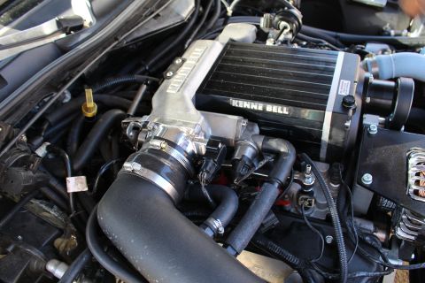 2003 Ford Crown Victoria - Detail of a Kenne Bell supercharger with a finned aluminum top sitting atop an engine, with black intake hoses and an alternator at right.