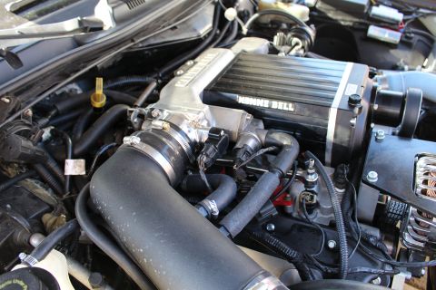 2003 Ford Crown Victoria - Three-quarter view of a Kenne Bell-supercharged engine showing a finned blower top, black intake hose and chrome alternator at right.