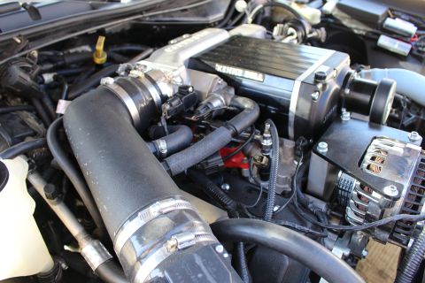 2003 Ford Crown Victoria - Engine bay close-up of a Kenne Bell supercharger and throttle body with clamped intake hoses and a polished chrome alternator on the right.