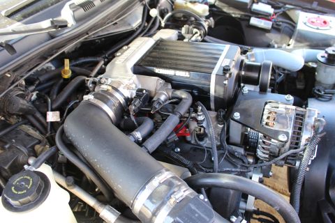 2003 Ford Crown Victoria - Wider engine-bay view of a Kenne Bell supercharger with a black intake hose, throttle body and a polished chrome alternator at right.