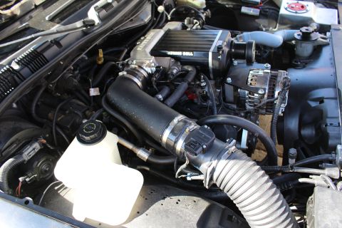 2003 Ford Crown Victoria - Open engine compartment featuring a Kenne Bell supercharger, white coolant reservoir, throttle body and a ribbed flexible air intake hose.