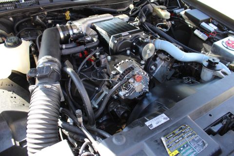 2003 Ford Crown Victoria - Three-quarter engine-bay shot of a Kenne Bell supercharger above a chrome alternator, with a ribbed air intake and battery in view.