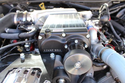 2003 Ford Crown Victoria - Close-up of a black Kenne Bell supercharger showing its finned aluminum top and belt-driven drive snout in the engine bay.