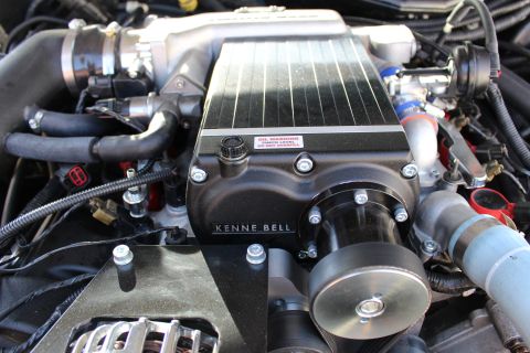 2003 Ford Crown Victoria - Detail of a black Kenne Bell supercharger's finned top with an oil-level warning label and oil cap, plus its drive snout pulley below.