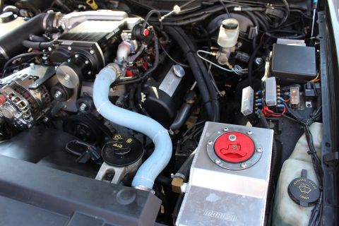 2003 Ford Crown Victoria - Engine bay showing a polished aluminum Moroso catch tank with a red battery disconnect knob beside a blue silicone hose and washer reservoi…