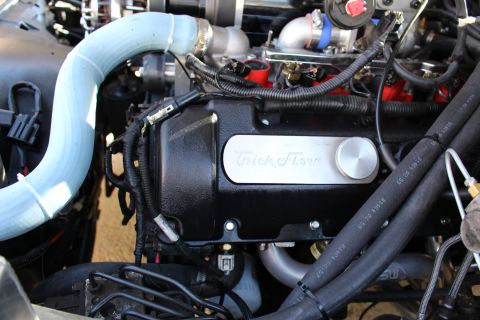 2003 Ford Crown Victoria - Engine bay close-up of a black Trick Flow valve cover routed beside a curved light-blue silicone tube and red fuel injectors.