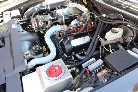 2003 Ford Crown Victoria - Wide engine bay view of a Kenne Bell supercharged motor with Trick Flow valve cover, blue silicone hose and brake master cylinder.