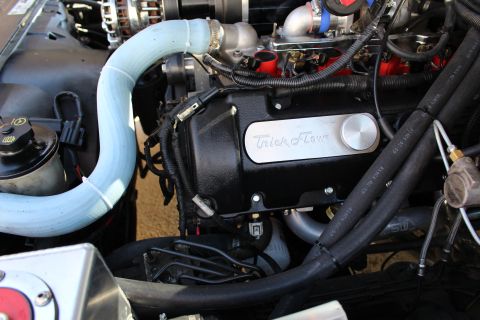 2003 Ford Crown Victoria - Engine bay close-up of a black Trick Flow valve cover beneath a light-blue silicone hose and red ignition coils.