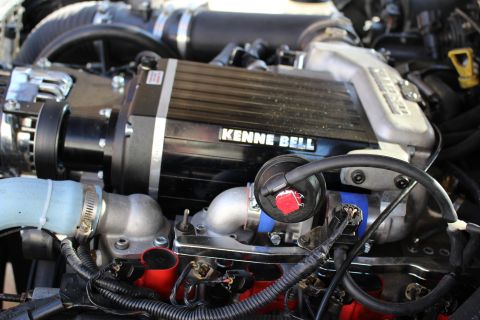 2003 Ford Crown Victoria - Engine bay detail of a Kenne Bell supercharger above an aluminum intake elbow, red ignition coils and chrome alternator.
