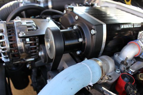 2003 Ford Crown Victoria - Engine bay close-up of the Kenne Bell supercharger drive pulley and belt beside a chrome alternator and blue silicone hose.