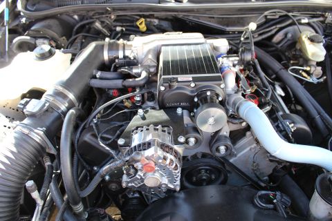 2003 Ford Crown Victoria - detailed engine bay showing a Kenne Bell supercharger atop the intake with a polished chrome alternator and blue piping.