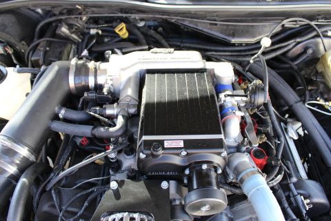 2003 Ford Crown Victoria - Overhead view of a black finned Kenne Bell intercooler unit bearing an oil warning label, installed atop an engine.