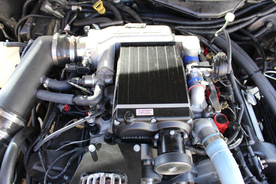 Black finned supercharger intercooler with red oil warning sticker on engine