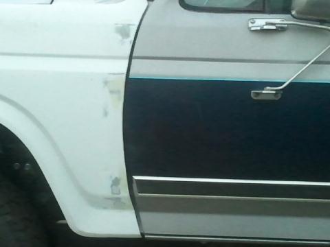 1986 Ford Bronco - Ford truck fender and door with chrome trim, undergoing bodywork.