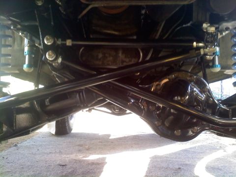 1986 Ford Bronco - The undercarriage of a vehicle is visible, suspension and drivetrain parts.