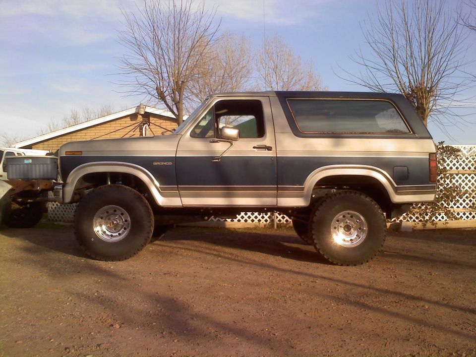 Lifted Ford Bronco with blue and silver two-tone paint, sitting on large off-road tires