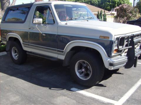 1986 Ford Bronco - This Ford Bronco features a two-tone paint scheme with a dark blue stripe separating the gray upper and lower body panels.