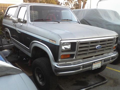1986 Ford Bronco - This 1986 Ford Bronco features a distinctive silver and black two-tone paint scheme and a prominent front grille.