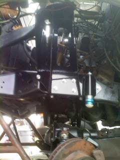 1986 Ford Bronco - Close-up view of the suspension system and engine components of a vehicle, with a Supermotors logo at the bottom.