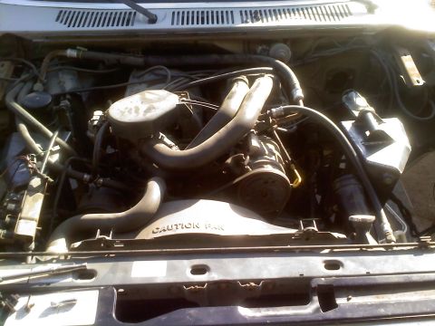 1986 Ford Bronco - Engine bay view showing hoses, fan, and other components. Text on fan shroud indicates caution.