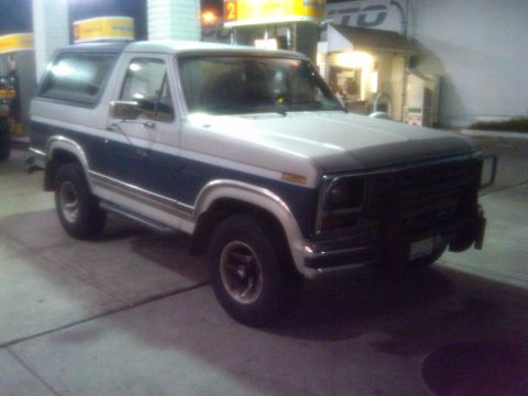 1986 Ford Bronco - Two-tone 1986 Ford Bronco with blue and white paint, seen at a gas station.