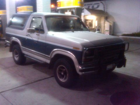 1986 Ford Bronco - This two-tone Ford Bronco is parked at a gas station under the lights.