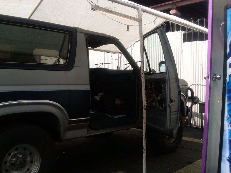 1986 Ford Bronco with driver door open, showing interior and engine bay