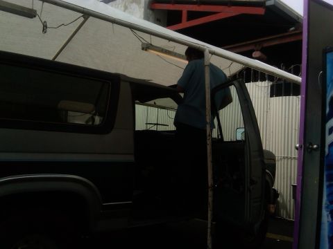 1986 Ford Bronco - Side view of a 1986 Ford Bronco with the driver's door open, a person is visible inside.