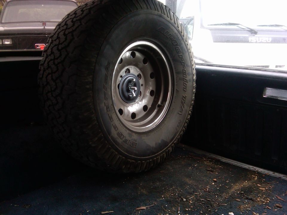 Spare tire mounted inside a vehicle, with another vehicle visible in the background