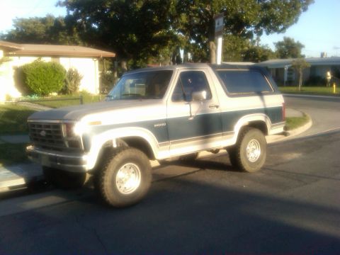 1986 Ford Bronco - This two-tone 1986 Ford Bronco is parked on a street in front of a house.