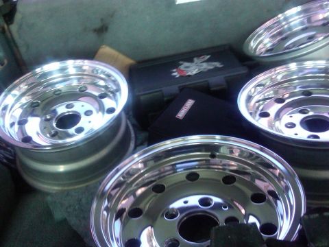 1986 Ford Bronco - Four shiny chrome wheels are visible in the back of a vehicle, possibly for transport or storage.